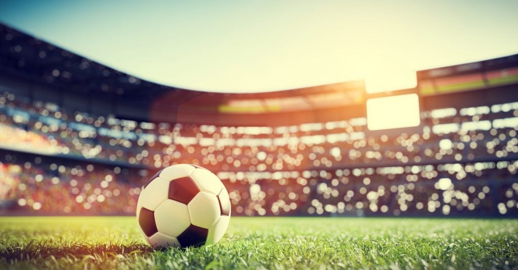 Copa do Brasil: bola no gramado em estádio lotado. Representação (iStock).